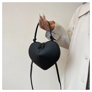 Detail of a black heart-shaped handbag featuring dual zippers and elegant top handle