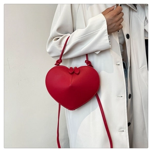 Detail of red heart-shaped crossbody bag in polished PU leather with zip and strap