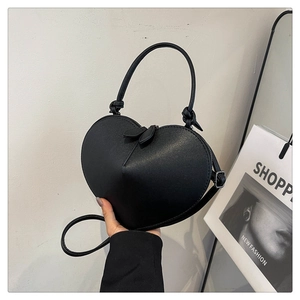 Detail of the heart-shaped crossbody bag featuring twin heart zippers and sleek top handle