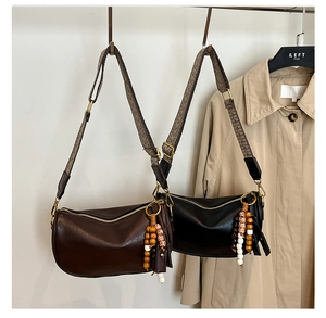 Detail of Boston bag featuring woven wide strap and bohemian wooden bead tassel pendant