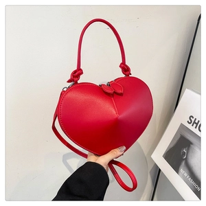 Detail of red heart-shaped handbag with glossy leather finish and dual heart zip pullers