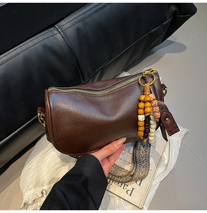 Detail of dark brown Boston bag with woven strap and vintage beaded tassel ornament