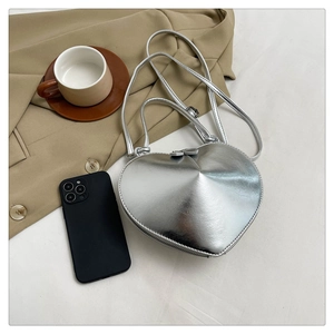 Detail view of heart-shaped silver metallic handbag with smooth mirror finish and handles