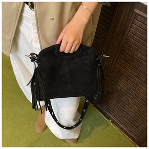 Detail einer schwarzen Wildledertasche mit langen Fransen und breitem Ösenschultergurt