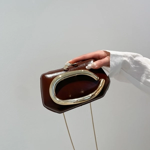 Retro dark brown patent leather clutch with a large gold C-shaped metal handle and chain