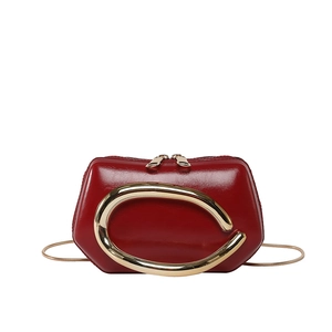 Glossy red leather mini bag with large gold C-shaped buckle and metal snake chain strap