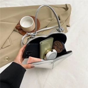 Glossy silver heart-shaped crossbody bag with spacious interior shown with daily essentials
