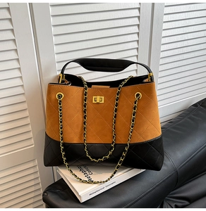 Detail of quilted two-tone handbag with gold turn-lock and suede flap on book
