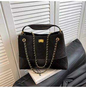 Detail of matte suede texture and gold chain strap on black quilted crossbody bag