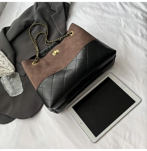 Macro view of vintage quilted tote bag with brown suede and black leather stitching detail