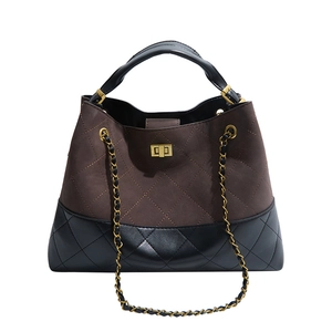 Detail of color-block suede handbag with quilted stitching and gold twist lock closure