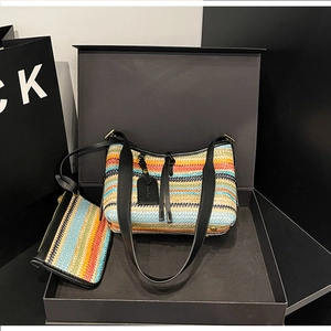 Detail of rainbow striped woven handbag set in a luxury black gift box with gold metal zipper