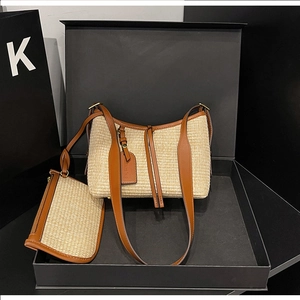Detail view of woven straw shoulder bag set with brown leather trim in a premium black box