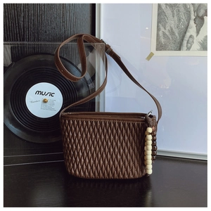 Detail of dark coffee pleated bucket bag featuring wooden bead charms and retro styling