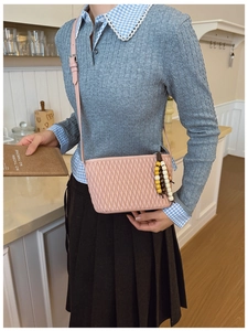 Detail of pink pleated bucket bag with beaded tassel and crossbody leather strap