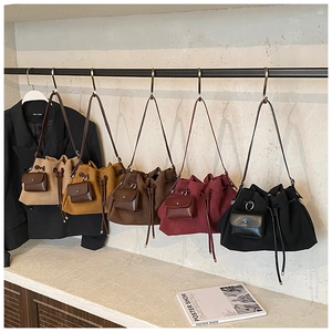 Close-up of matte suede bucket bags in five colors with mini charm pouches on display