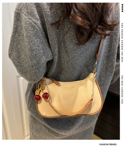Detail der cremeweißen Schultertasche mit Kirsch-Anhänger und eleganter Kette