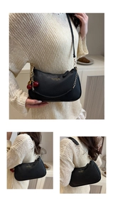 Detail der schwarzen Handtasche aus Kieselleder mit Goldkette und Kirsch-Anhänger