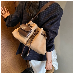 Detail of khaki frosted suede bucket bag with brown leather accents and drawstring closure