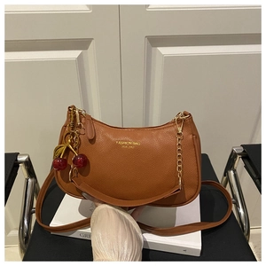 Detail of brown litchi pattern crescent bag with golden chain and cherry charm