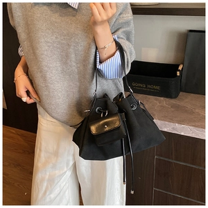 Detail of black canvas drawstring bucket bag with mini zipper pouch and leather strap