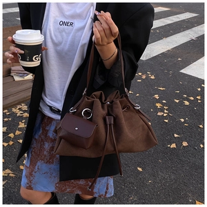 Dettaglio della borsa a secchiello in pelle scamosciata marrone con mini pochette appesa