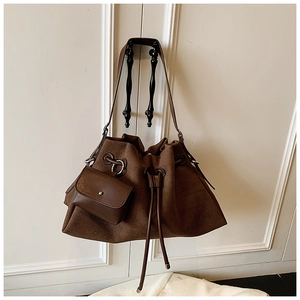 Close-up of brown matte drawstring bucket bag with detachable charm and shoulder strap