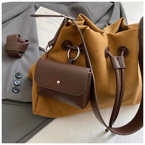 Dettaglio di una borsa a secchiello in pelle scamosciata color zenzero su una giacca grigia