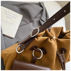 Detailed macro view of caramel suede drawstring bucket bag with silver metal ring buckle