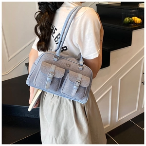 Detail of light blue bowling bag with texture fabric and front buckle pockets
