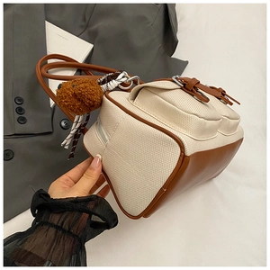 Detail view of canvas and leather contrast bowling bag with plush teddy bear charm