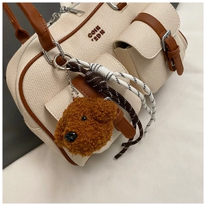 Detail of canvas bowling bag with leather trim, outer pockets and plush dog charm