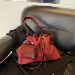 Retro burgundy frosted leather bucket bag with drawstring and silver hardware on chair