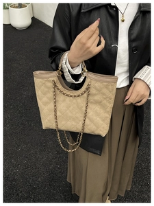 Close-up of quilted beige tote bag with elegant gold chain strap and diamond stitch texture