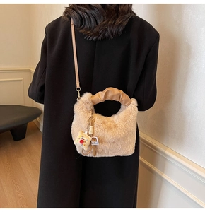 Dettaglio della borsa in peluche con manico in pelle marrone e ciondolo a forma di pane