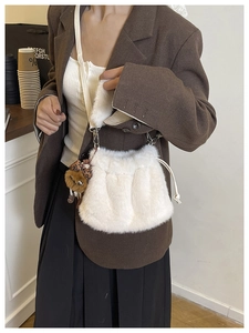 Close-up of white plush bucket bag with drawstring closure and cute bear pendant