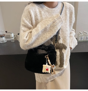 Dettaglio borsa a secchiello in peluche nero con ciondolo carino e tracolla in pelle