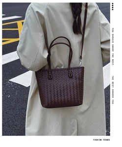Street style shot of a dark coffee woven tote bag paired with a beige trench coat