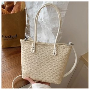 Detail of cream woven tote bag with adjustable shoulder strap and sturdy top handles