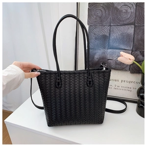 Close-up of black woven leather tote bag texture with elegant tulip vase background