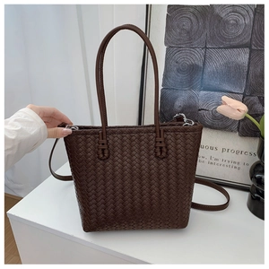 Detail of dark brown woven tote bag with adjustable strap and textured leather finish