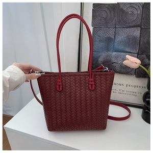 Detail of dark red woven leather tote bag featuring a removable shoulder strap and texture