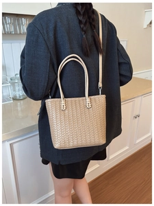 Detailed view of khaki woven tote bag with slim handles and silver metal hardware