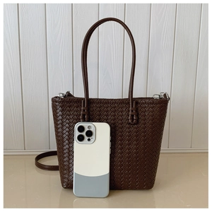 Detail of dark brown woven tote bag showing fine texture and detachable shoulder strap