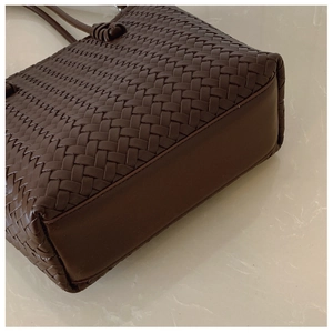 Close-up of dark brown woven leather texture and smooth base of a large tote bag