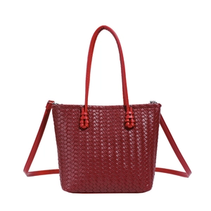 Detail view of deep red woven tote bag featuring leather texture and silver metal hardware