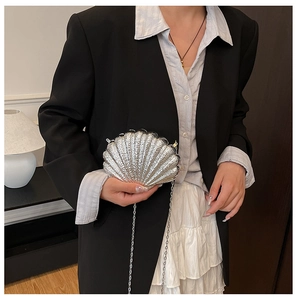 Detail of silver shell-shaped clutch bag with textured finish and delicate metal chain