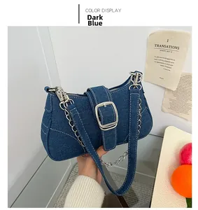 Dettaglio della borsa denim blu scuro con fibbia argentata quadrata e tracolla a catena