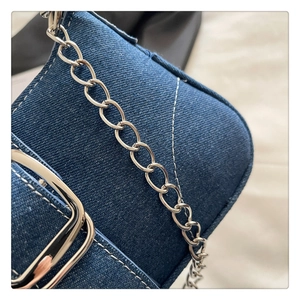Dettaglio borsa a spalla in denim con cuciture trapuntate bianche e catena d'argento