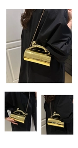 Close-up of golden cylindrical evening clutch with horse-shaped handle and metal chain strap